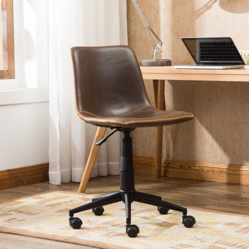 A Swiveling Office Chair in front of a table with a laptop and table lamp on it, all in a home office.
