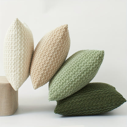 Four knitted pillows in beige, brown, green, and olive on a light background