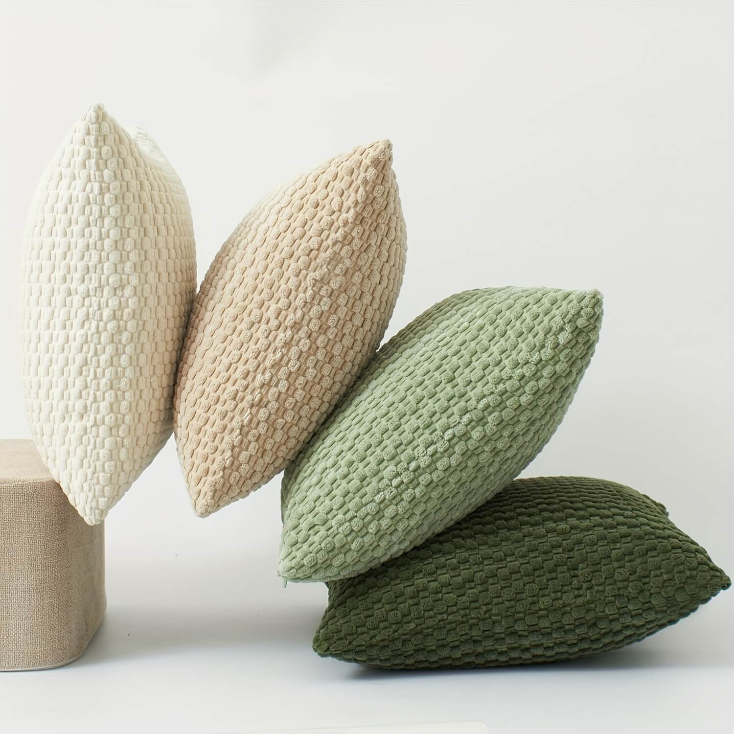 Three knitted pillows in beige, green, and brown on a light background