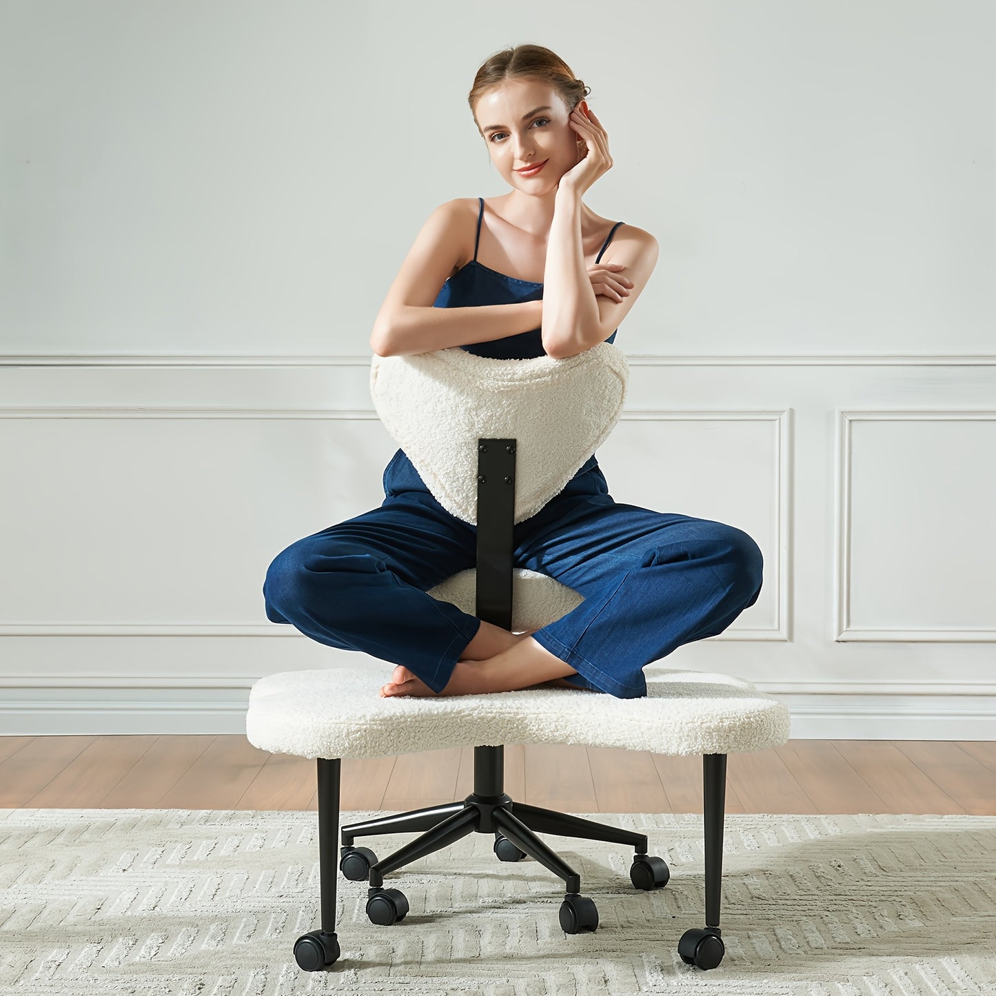 Woman sitting on a unique chair with a white cushioned seat and backrest in a room with white walls.