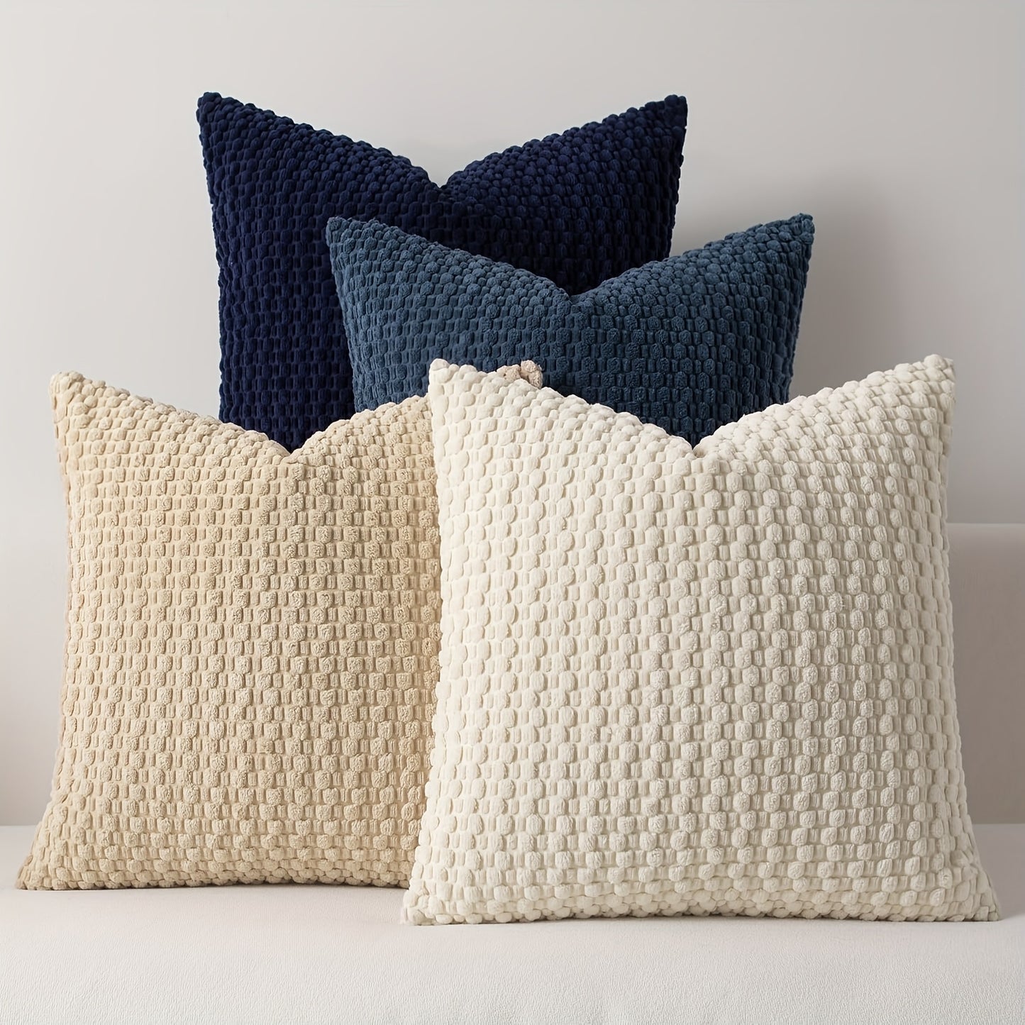 Three textured pillows in navy and beige on a light background