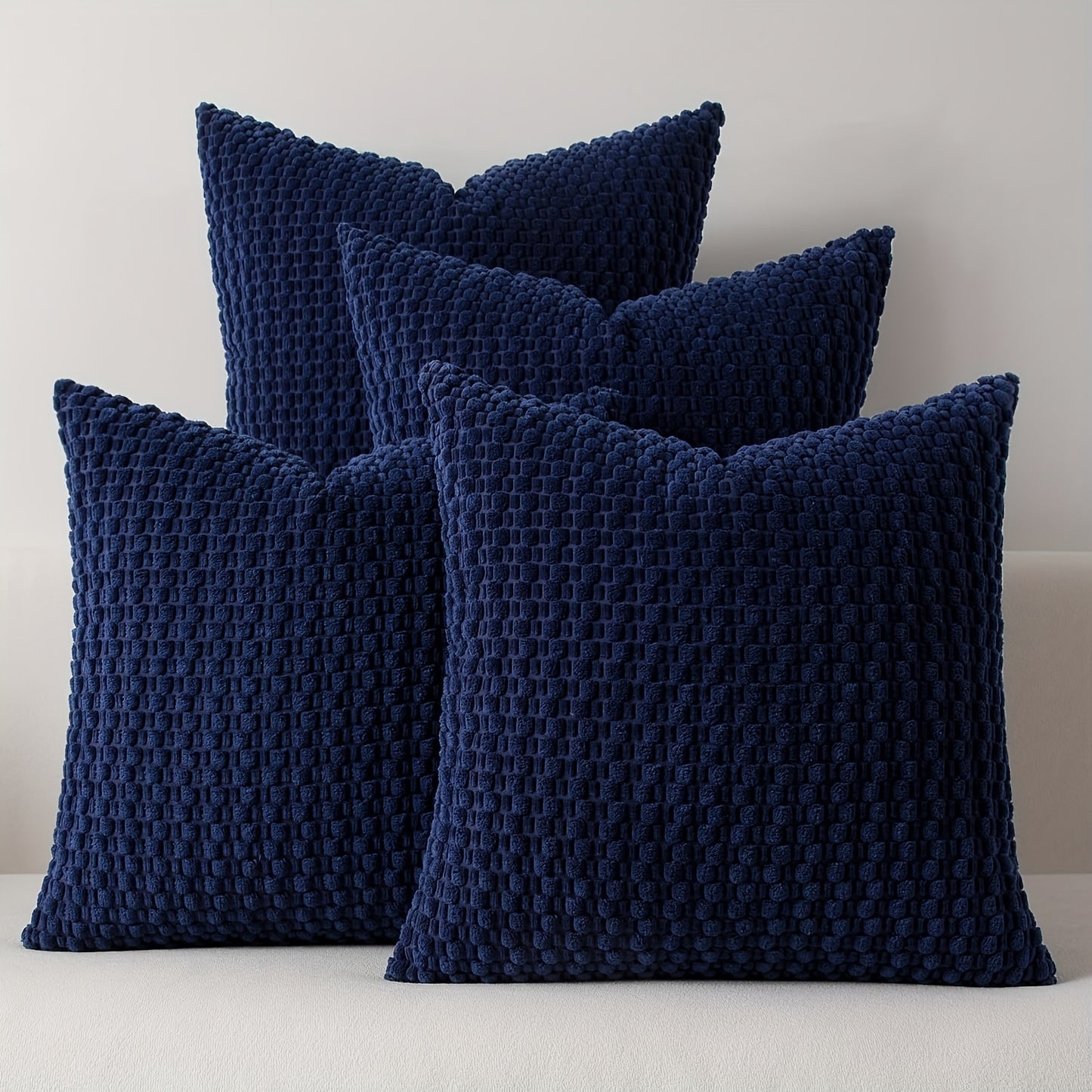 Four navy blue textured pillows on a light gray background