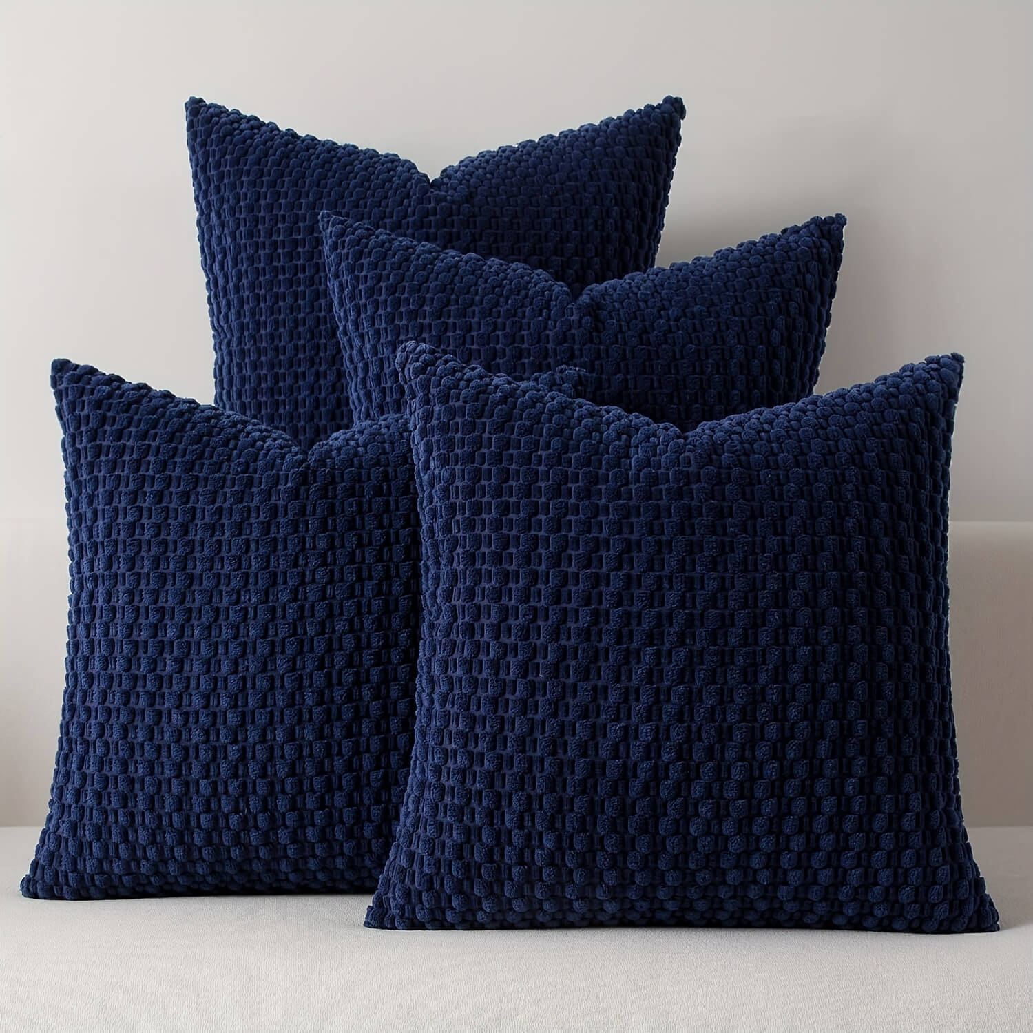 Four navy blue textured pillows on a light gray background