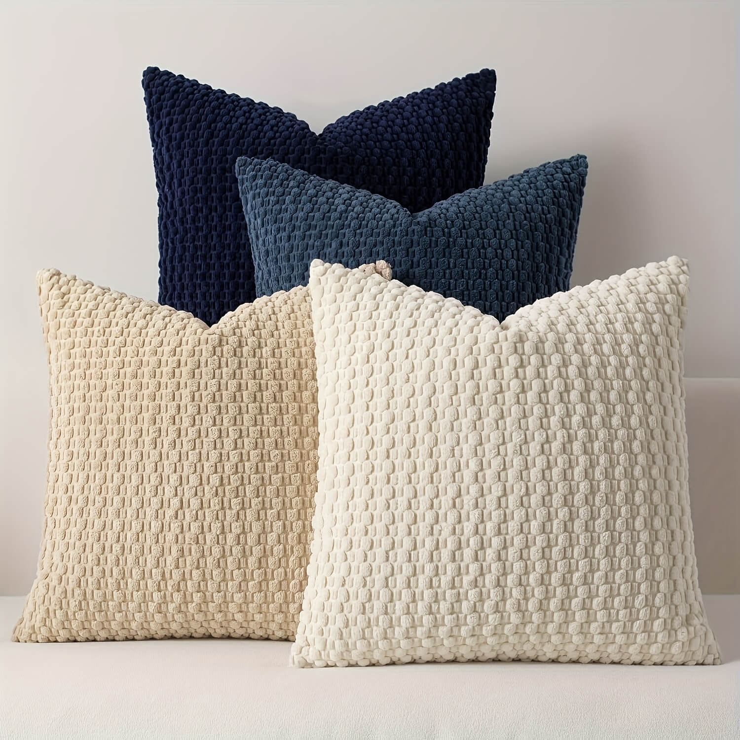 Two navy textured pillows and two beige textured pillows on a light background