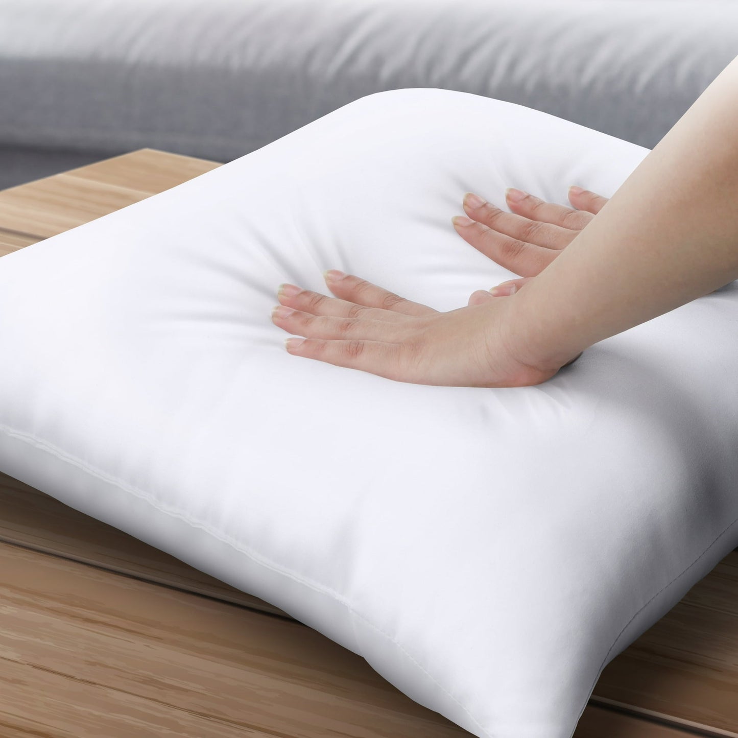 White pillow on a wooden surface with a hand touching it
