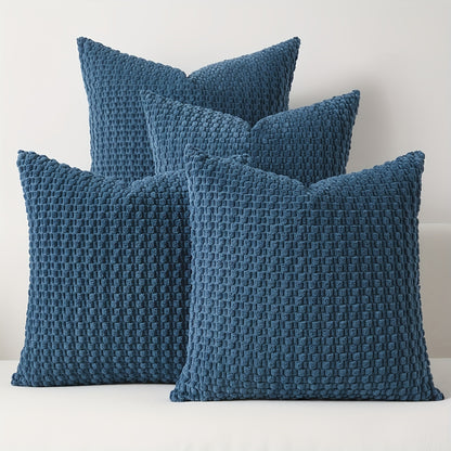 Four blue textured pillows on a white surface with a light gray background