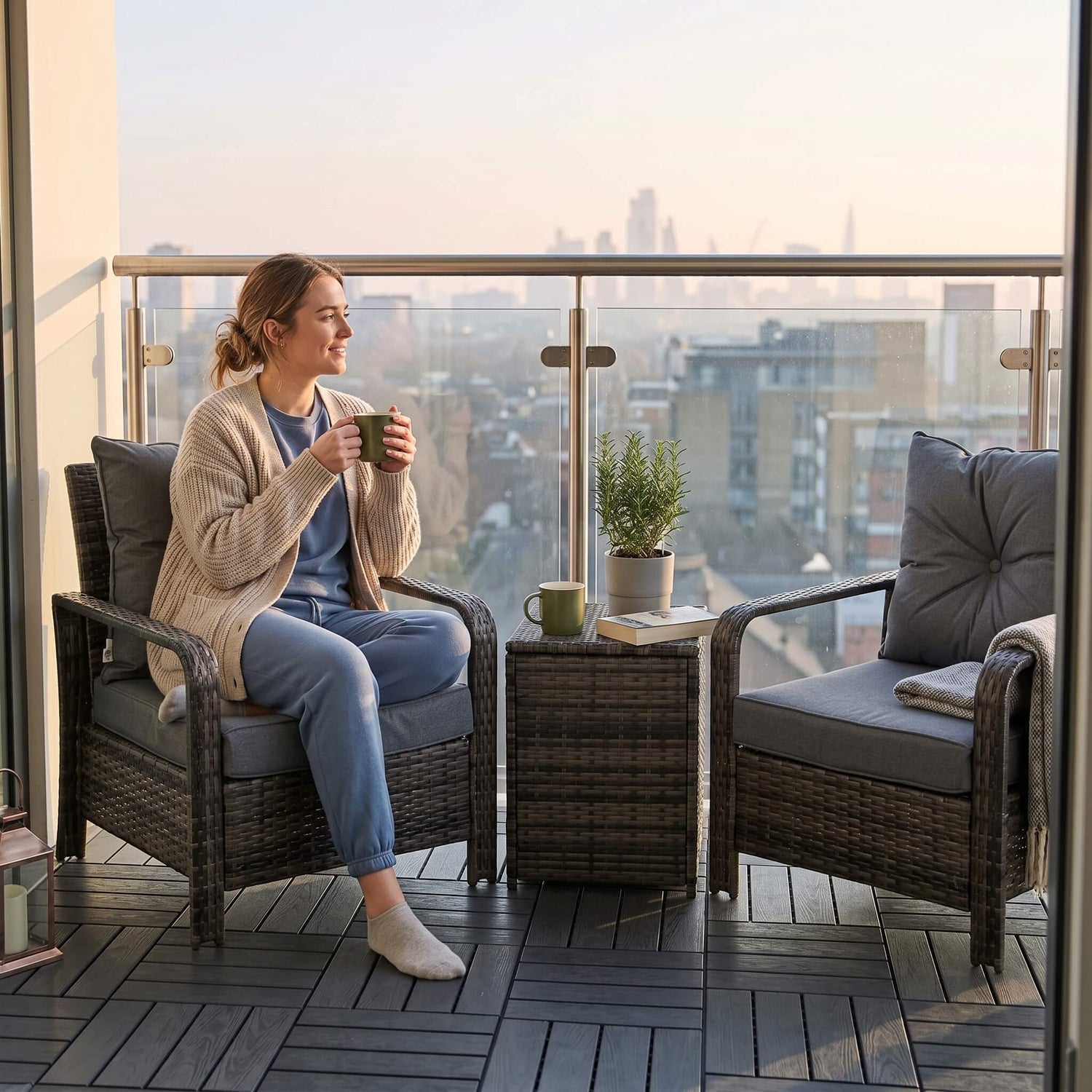 Woman sitting on a balcony with a view of a cityscape, holding a mug.