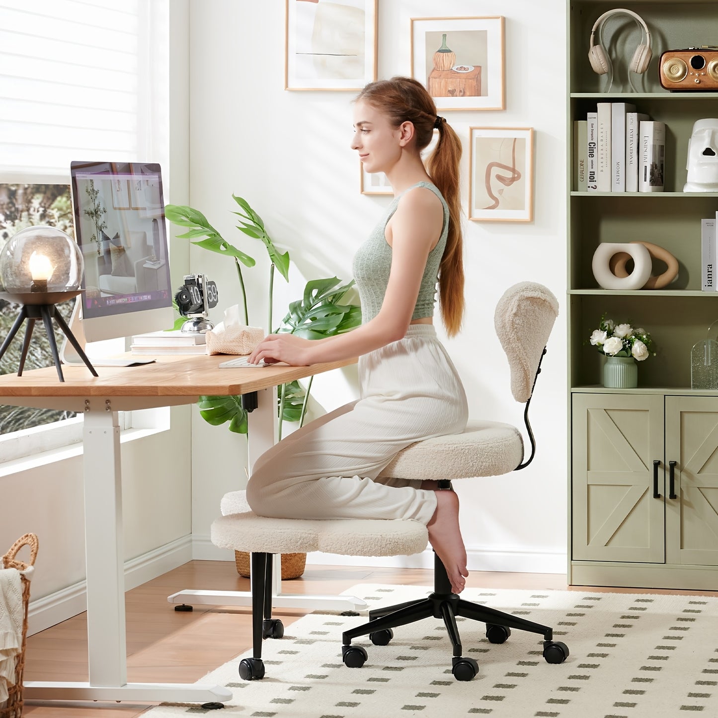 Woman sitting on a kneeling chair at a desk in a home office setting.