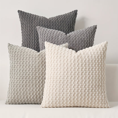Four textured pillows in gray and white on a light background
