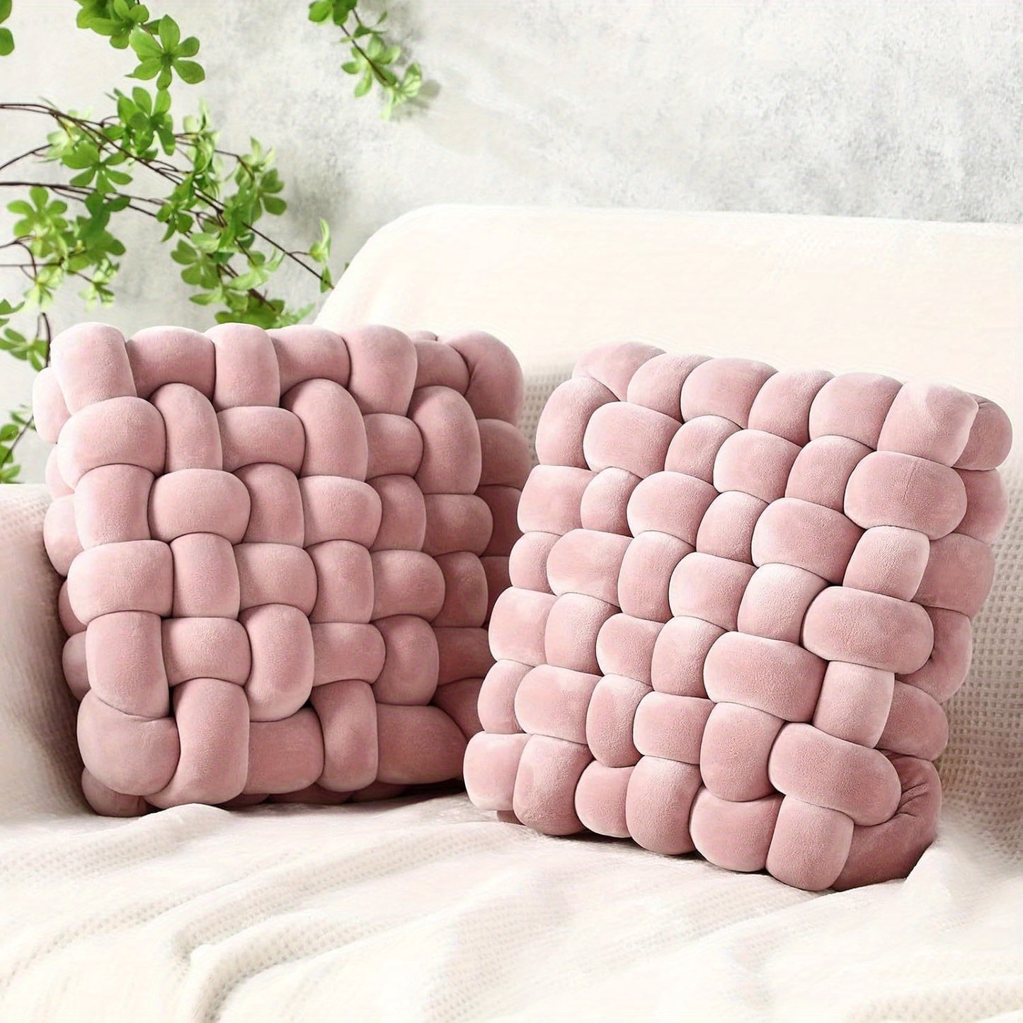Two pink textured pillows on a white surface with a light gray background.