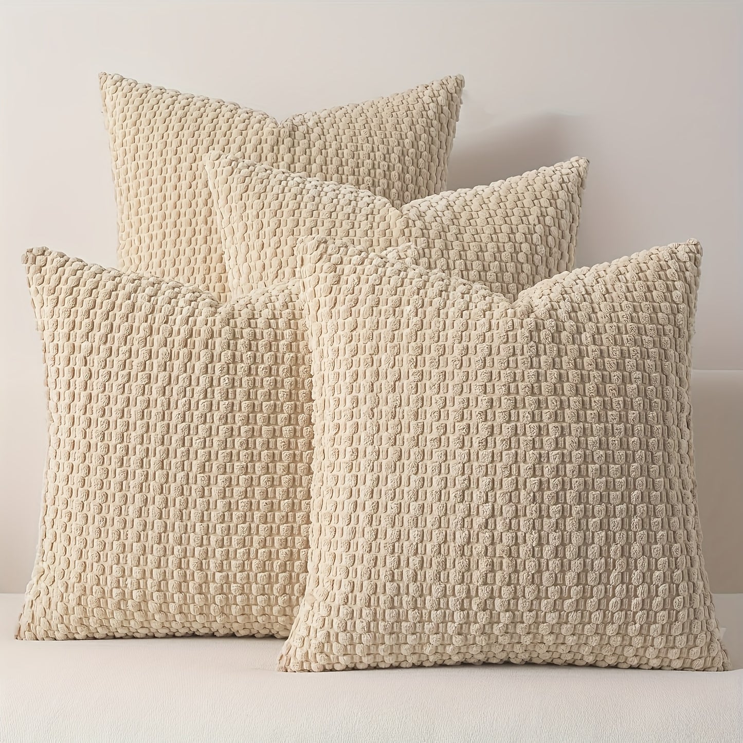 Three textured beige pillows on a light background