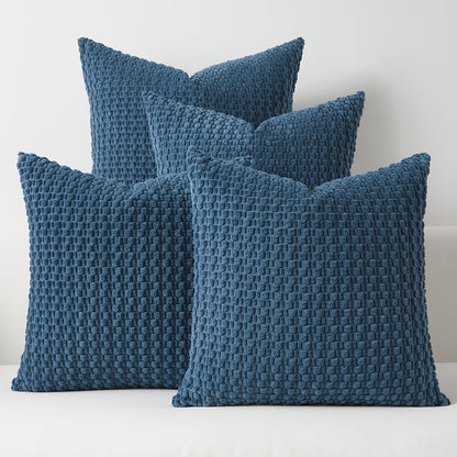 Four blue textured pillows on a white surface with a light gray background