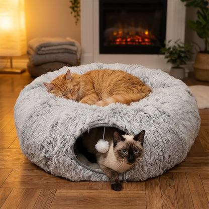 Two cats in a cat donut with a fireplace in the background