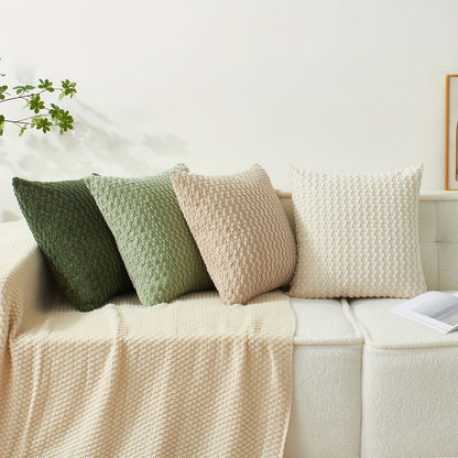 Four textured pillows on a beige sofa with a neutral background
