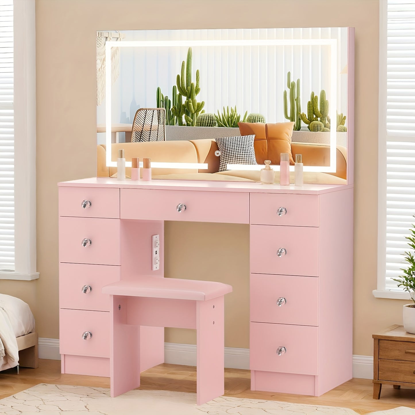 Pink vanity desk with mirror in a room with cacti and a bed.