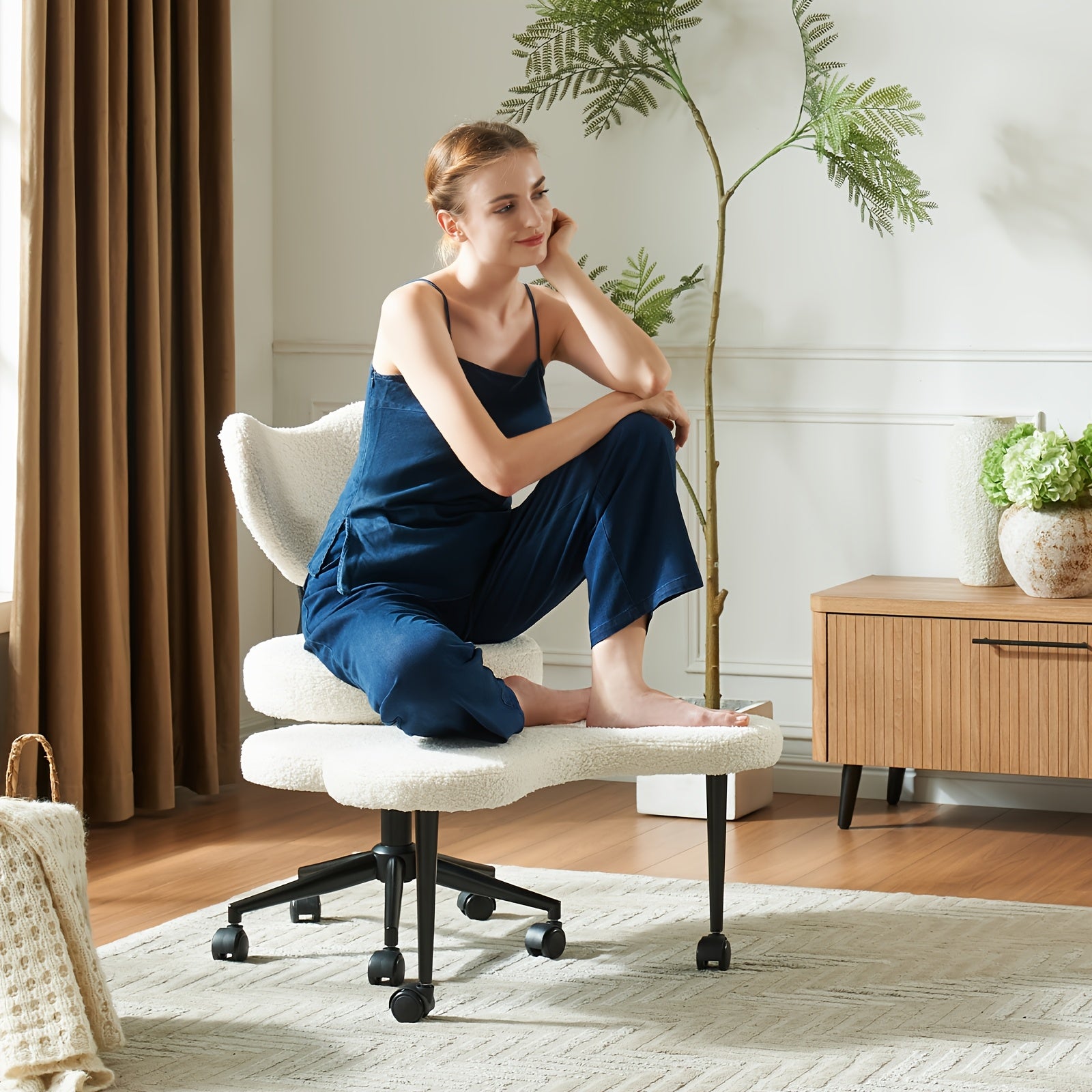 Woman in a blue outfit sitting on a white office chair in a home office setting.