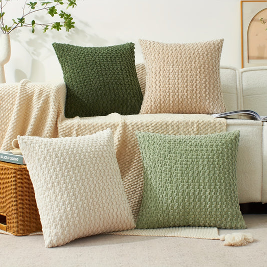 Knitted pillows in green and beige on a sofa with a plant and basket in the background.