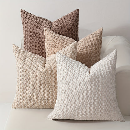 Textured throw pillows in various tones on a sofa against a neutral background
