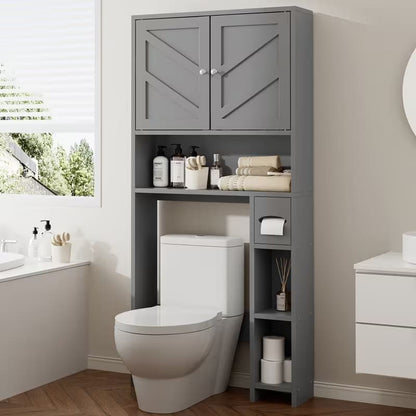 A tall gray toilet roll storage cabinet with two upper doors and open shelving, shown over a toilet in a real bathroom setting with a window, vanity, and wood floor.