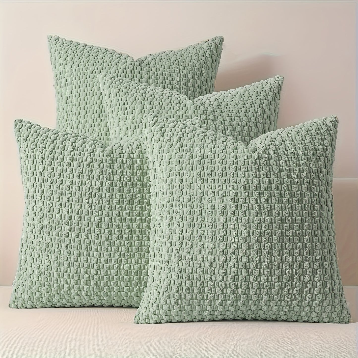 Three textured green pillows on a light pink background