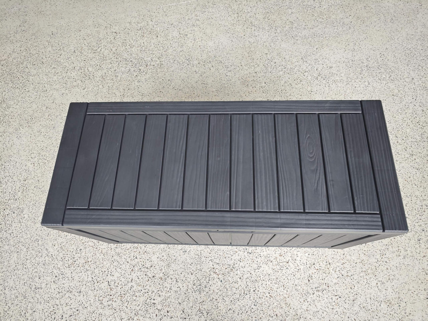 Dark gray wooden bench on a light gray surface
