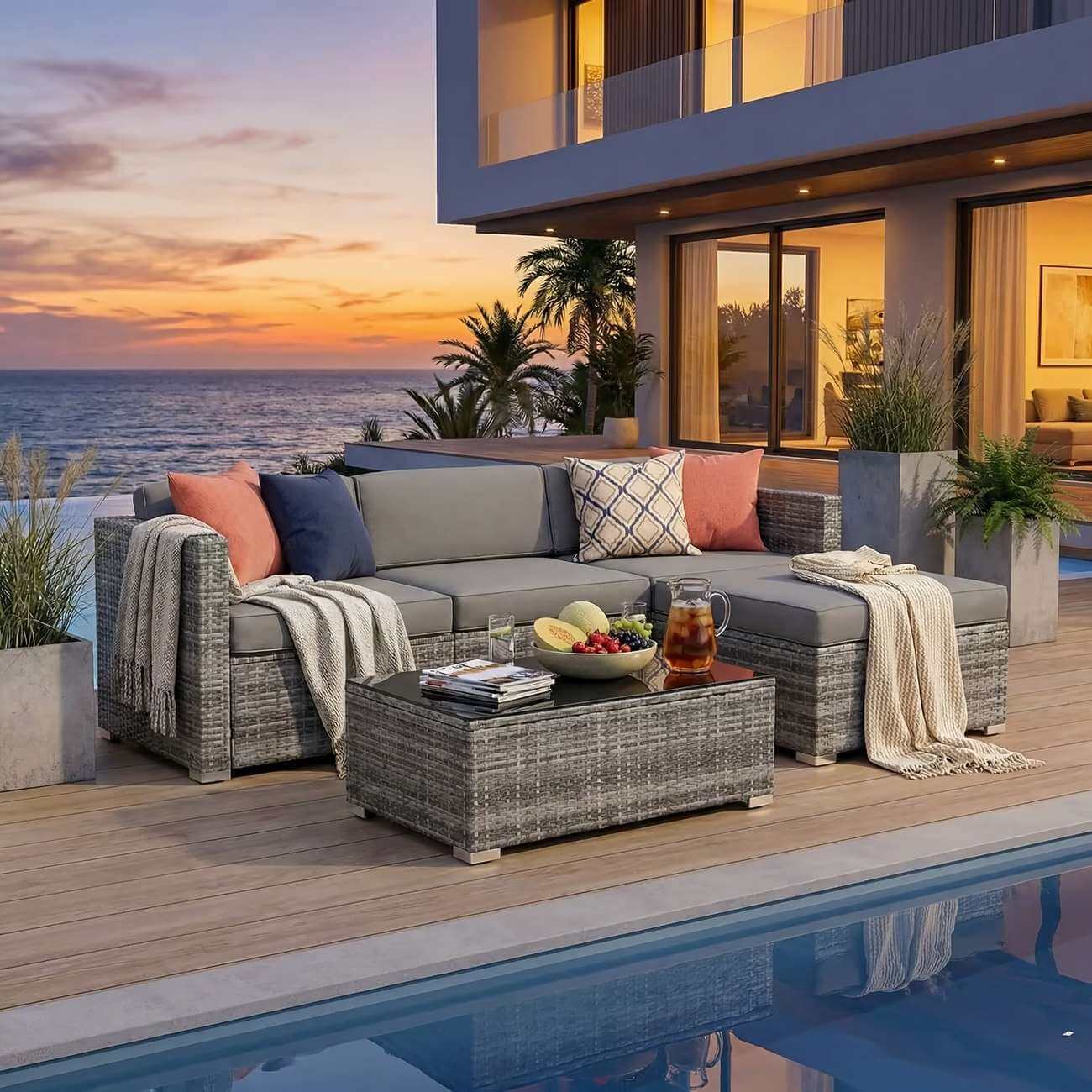 Outdoor patio with a sectional sofa, coffee table, and ocean view at sunset.