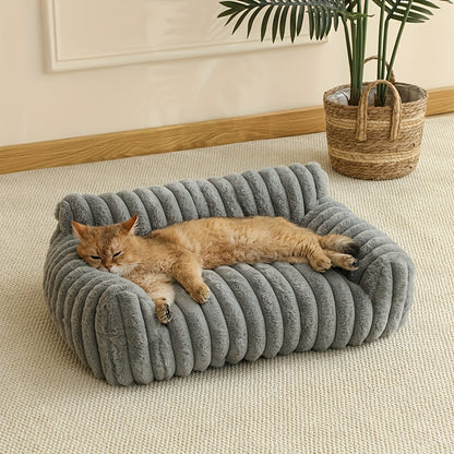 Cat sleeping on a plush gray cat sofa in a cozy room with a plant.