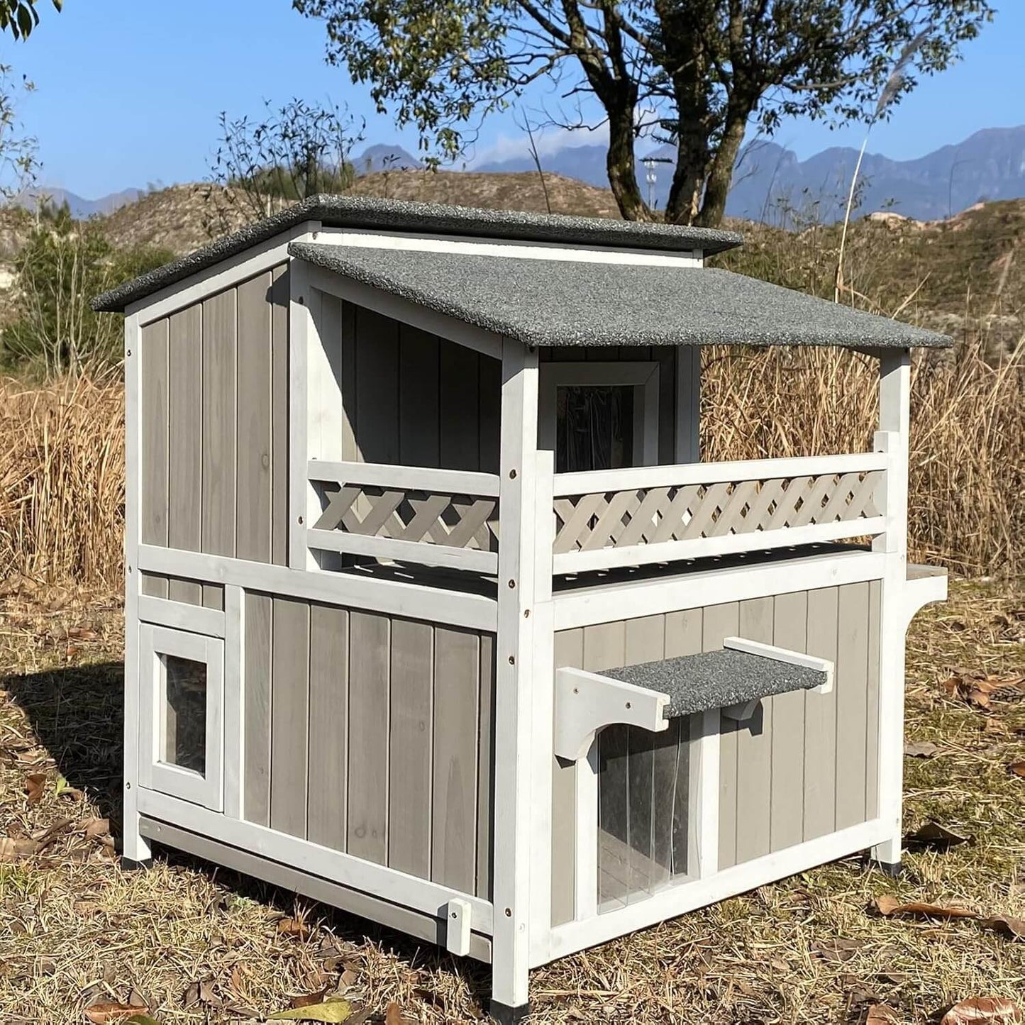 Wooden pet house with a gray roof in an outdoor setting with mountains in the background