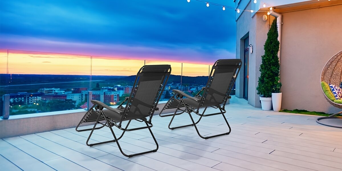 Two lounge chairs on a rooftop deck with a cityscape view at night.