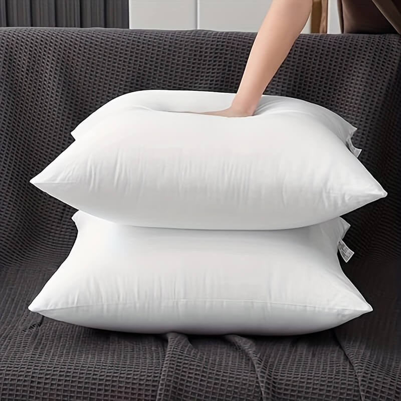 Two white pillows stacked on a dark gray textured surface
