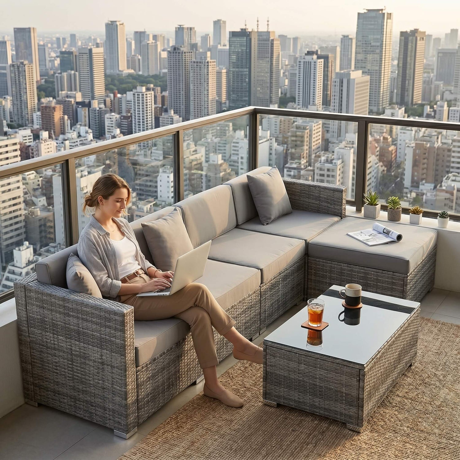 Woman using a laptop on a modern outdoor sofa with a cityscape view.