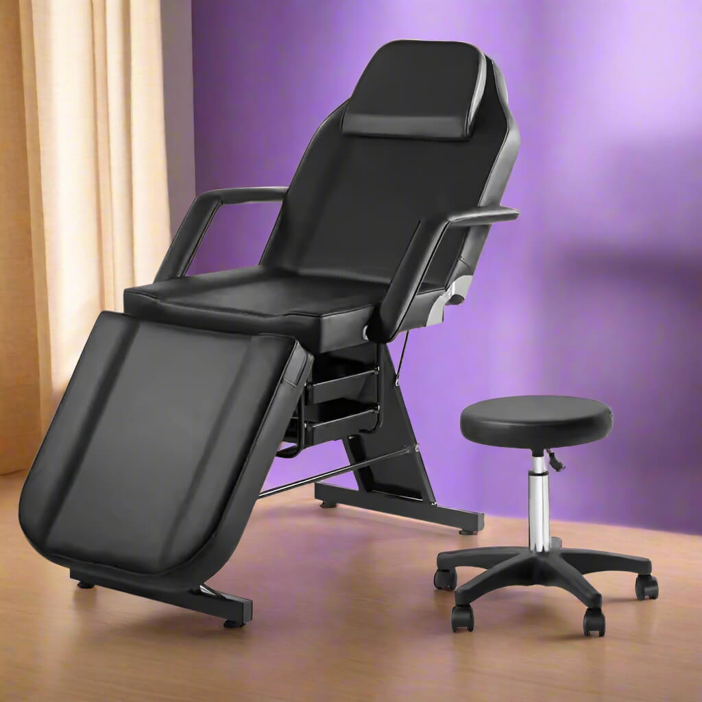 A black aromatherapy massage bed and black leather stool sold by WorkZen Interiors