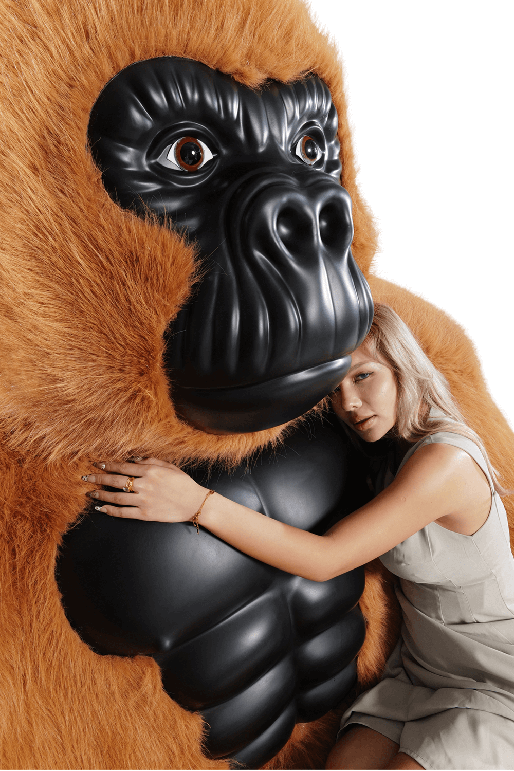 A brown inflatable gorilla sofa sold by WorkZen Interiors with a beautiful woman lying on it.