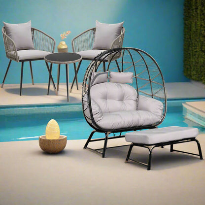 Modern outdoor furniture set with a chair, ottoman, and table by a pool.