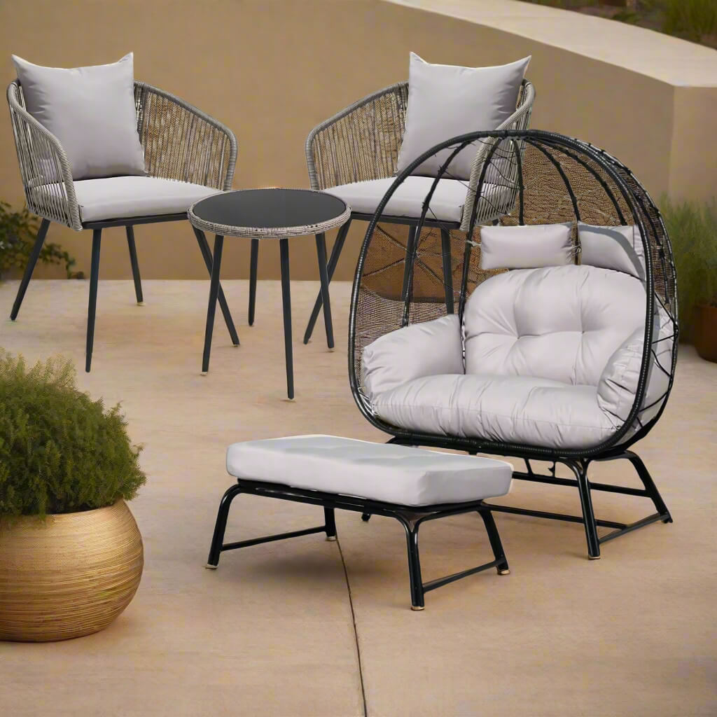 Outdoor furniture set with a round table, two chairs, and an ottoman on a patio.