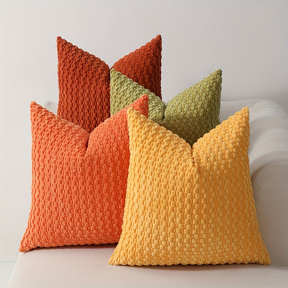 Colorful textured pillows on a sofa against a neutral background