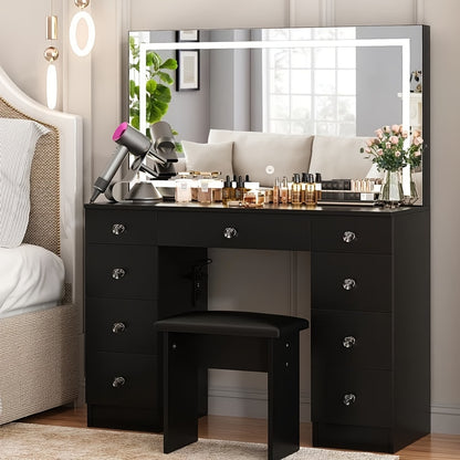 Black vanity desk with makeup items and a stool in a bedroom setting.
