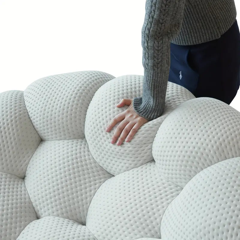 Person touching a textured bubble sofa with a plain background