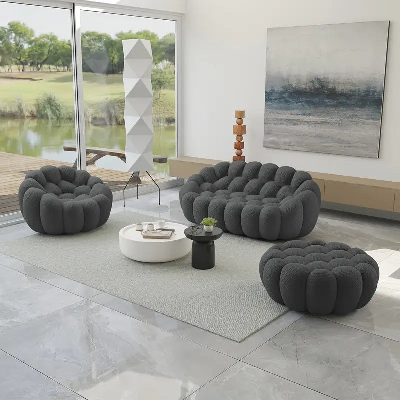 Modern living room with gray cloud-shaped sofa and ottoman in a bright room with large windows.