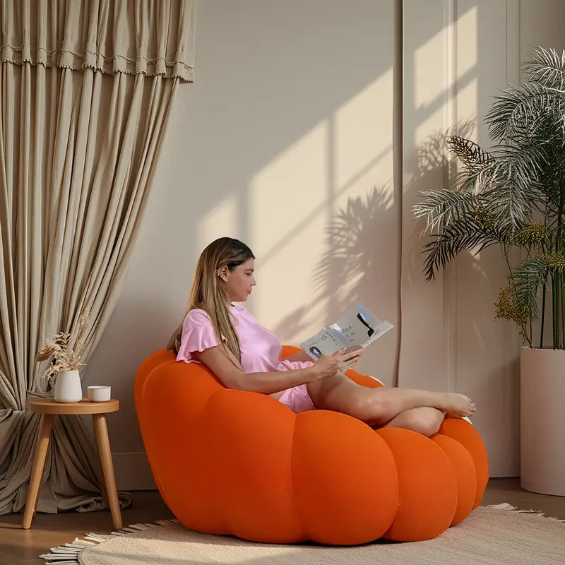 Woman reading a book on an orange curve sofa in a cozy room.