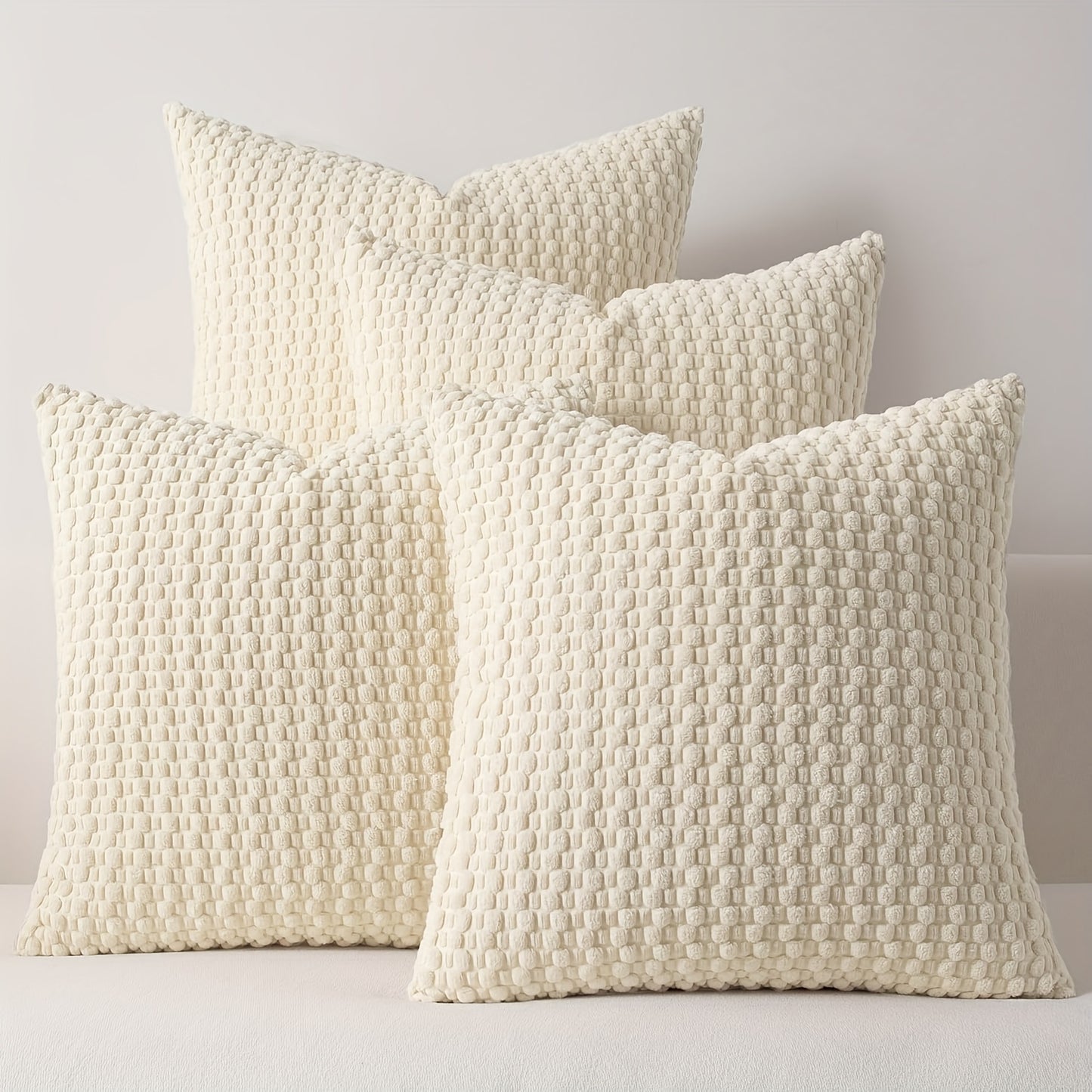 Four textured cream pillows on a light gray background