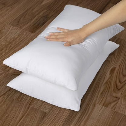 White pillows on a wooden floor with a hand touching one of them.