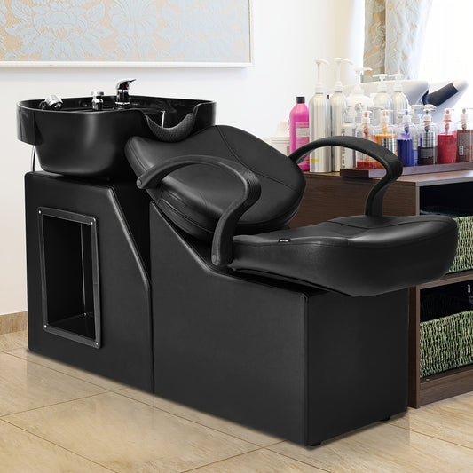 Black professional backwash unit in a salon setting with shampoo bottles in the background.