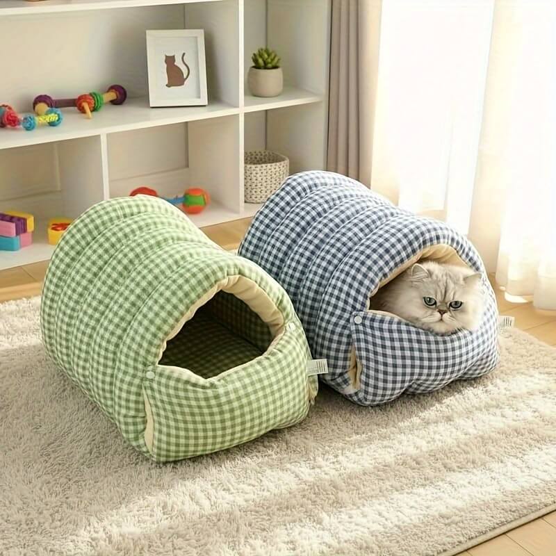 Two checkered wool cat cave, one green and one blue, with a cat peeking out on a carpeted floor.