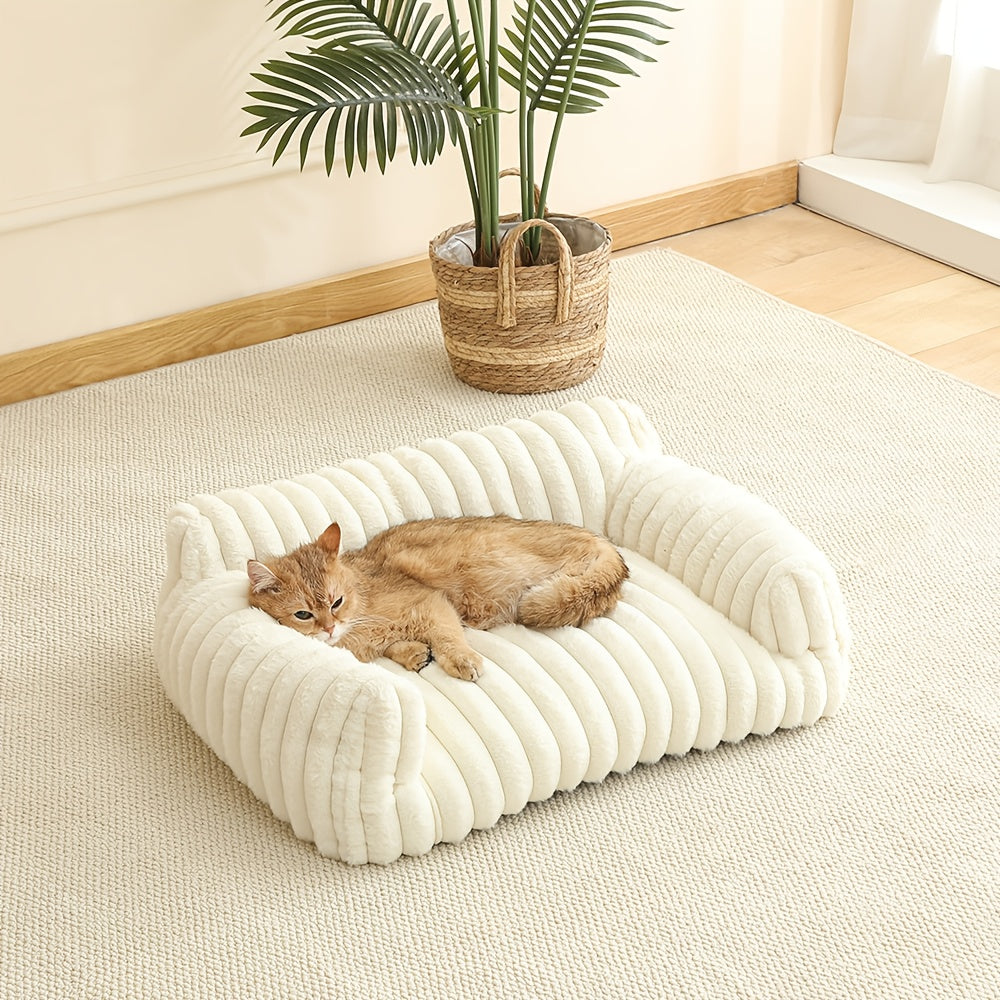 Cat lying on a fluffy white cat sofa in a room with a plant and wooden floor.