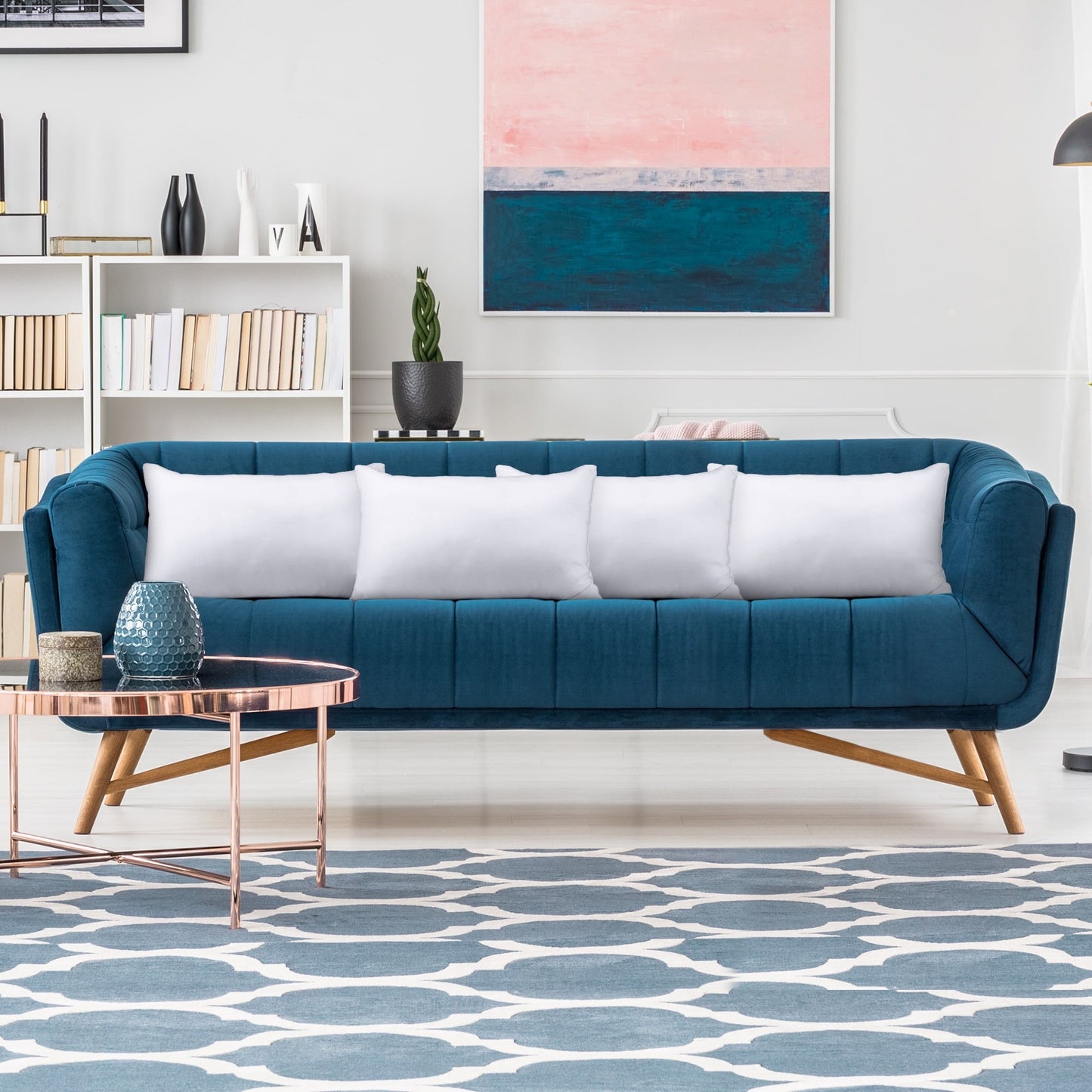 Modern living room with a blue sofa, white cushions, and a patterned rug.