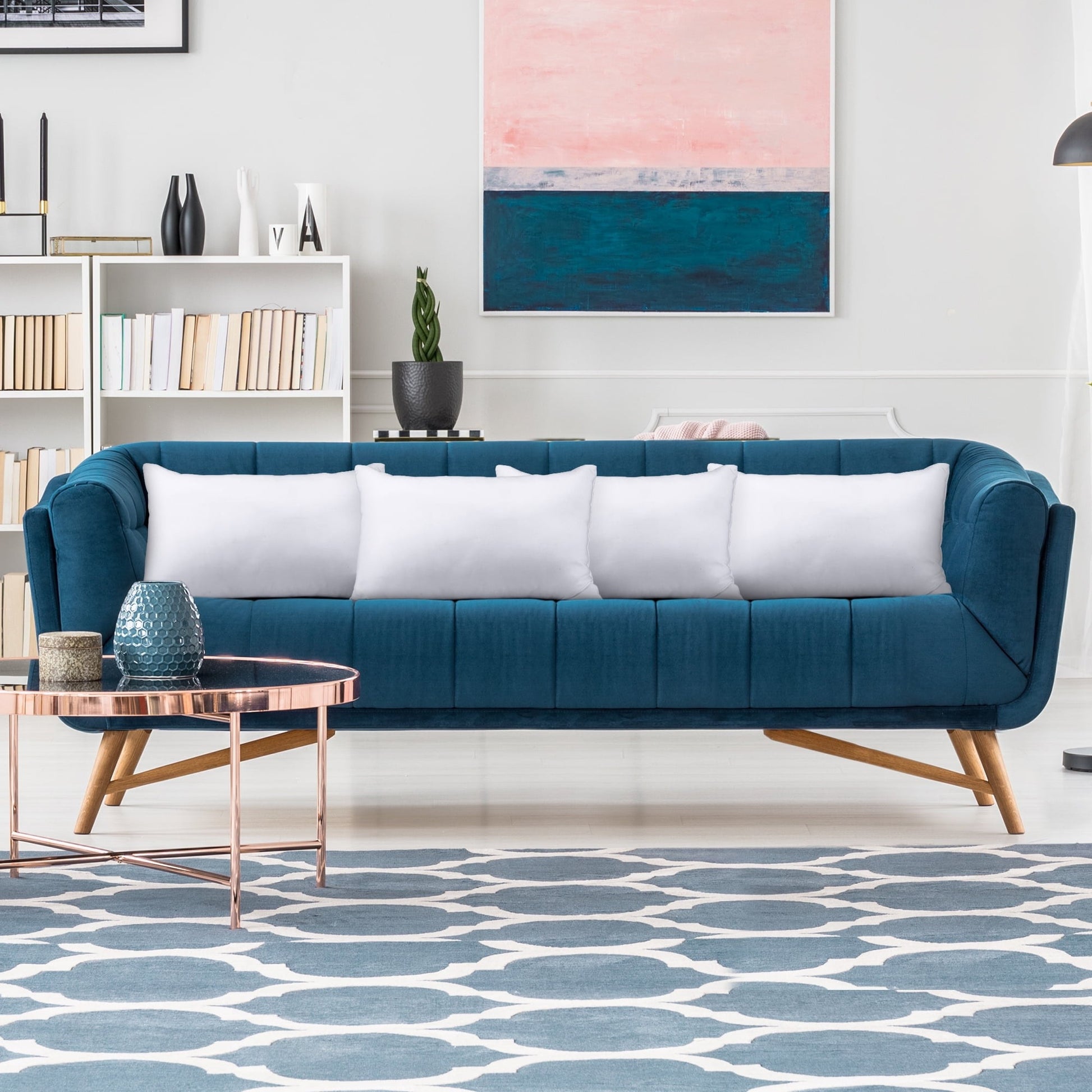 Modern living room with a blue sofa, white cushions, and a patterned rug.