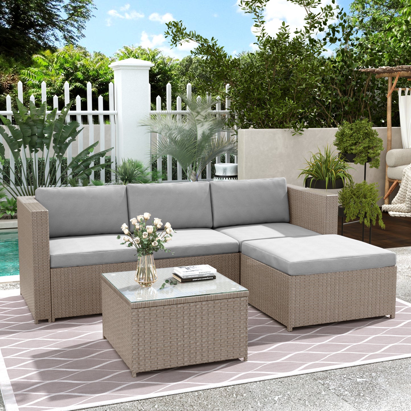 Outdoor patio set with sectional sofa and coffee table on a patio with pool and garden.