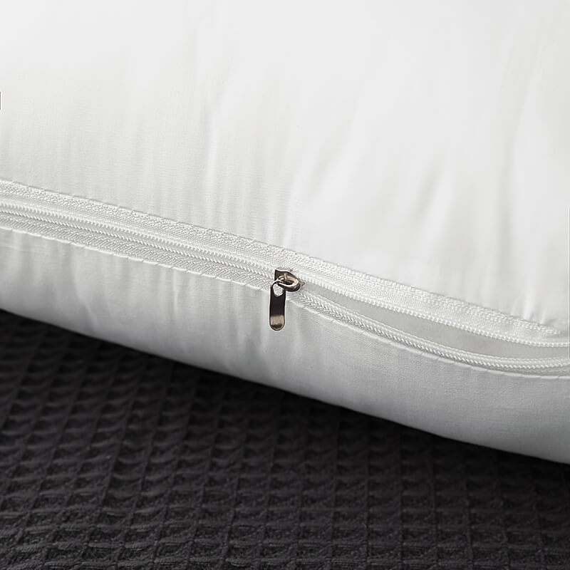 White pillow with a zipper on a textured dark surface