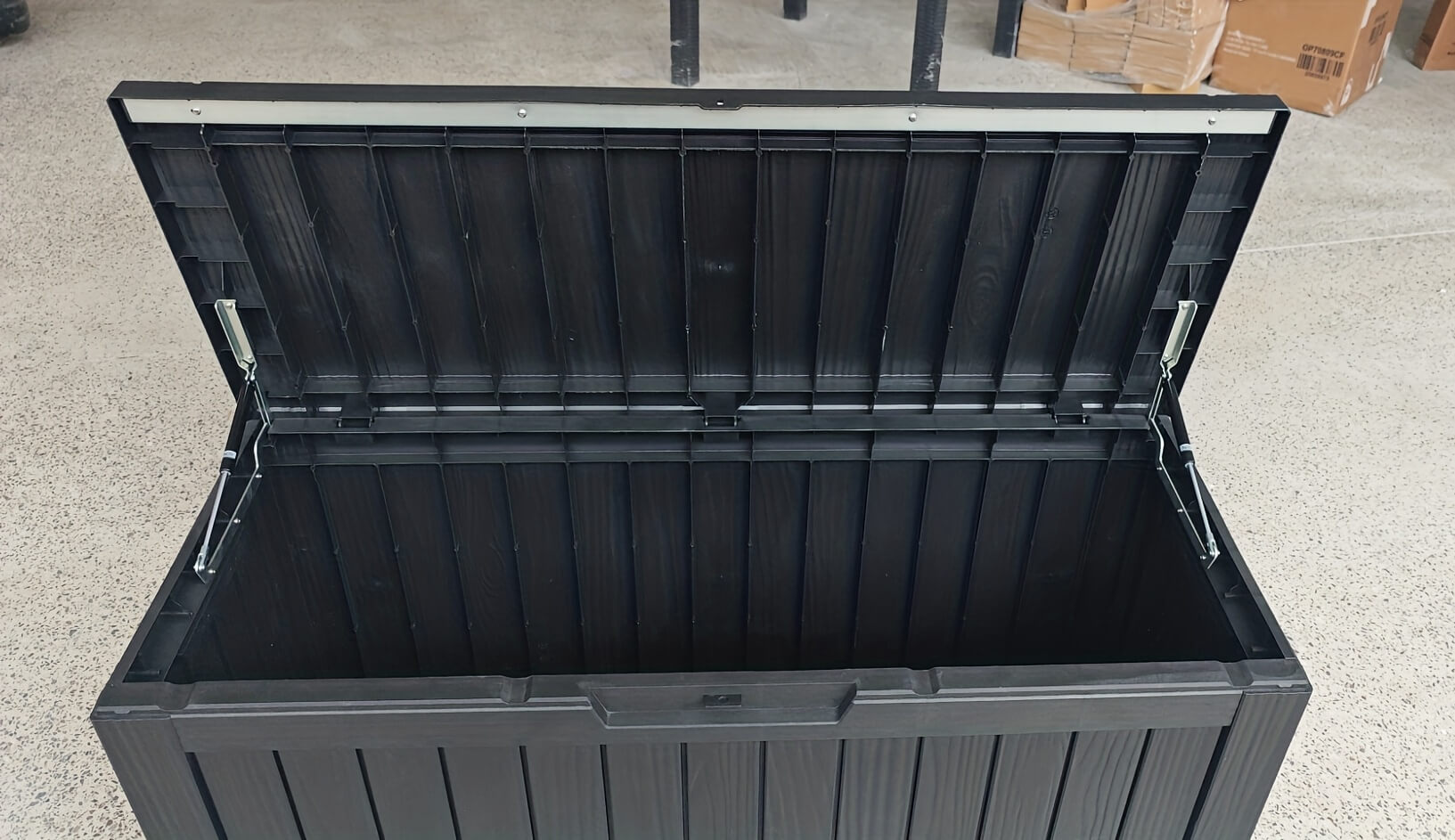 Black storage box with a lid on a concrete floor